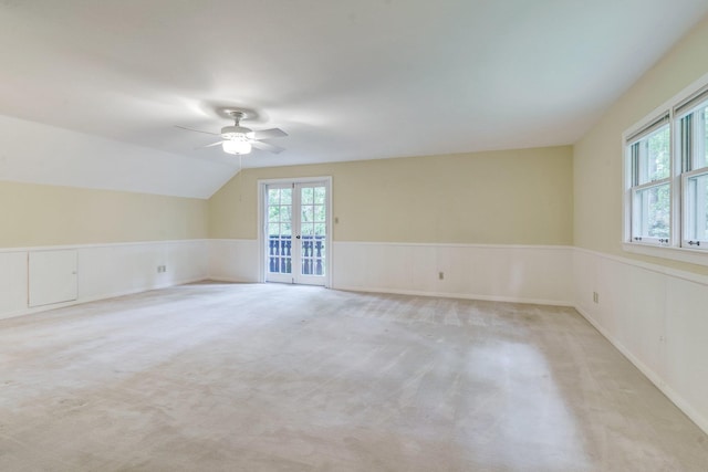 carpeted spare room with vaulted ceiling, a healthy amount of sunlight, ceiling fan, and french doors