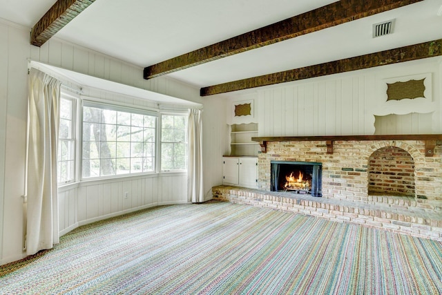 unfurnished living room with a brick fireplace, carpet floors, and beam ceiling