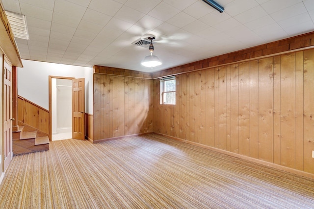 unfurnished room featuring light carpet and wood walls