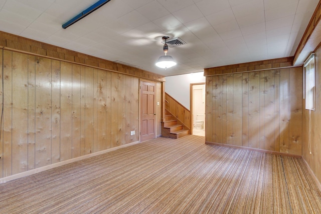 basement featuring light carpet and wood walls