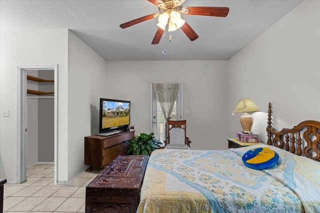 tiled bedroom featuring a walk in closet, a textured ceiling, ceiling fan, and a closet