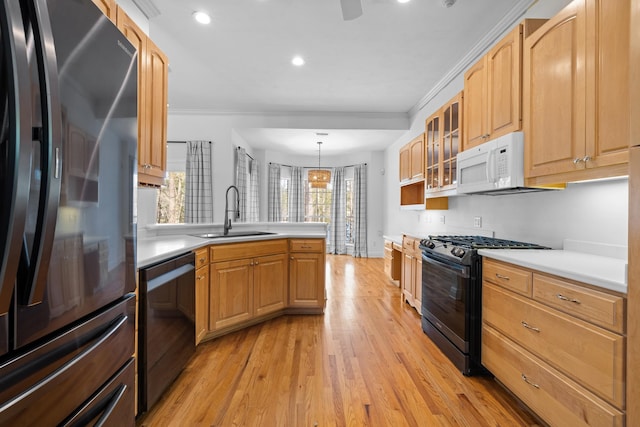 kitchen with hanging light fixtures, light hardwood / wood-style flooring, black appliances, sink, and crown molding