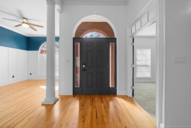 entryway with decorative columns, ornamental molding, a wealth of natural light, and light hardwood / wood-style flooring