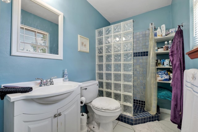 bathroom with toilet, a tile shower, vanity, and tile patterned floors