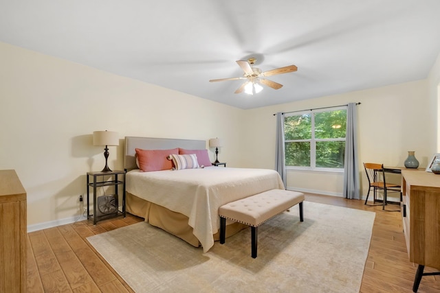 bedroom with baseboards, light wood-type flooring, and a ceiling fan