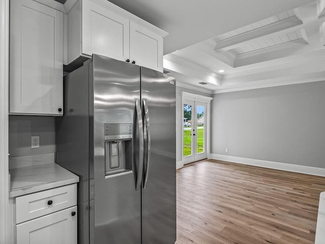 kitchen featuring crown molding, light hardwood / wood-style flooring, stainless steel fridge, a tray ceiling, and white cabinets