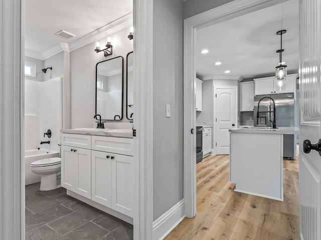 full bathroom with hardwood / wood-style flooring, vanity, ornamental molding, shower / washtub combination, and toilet