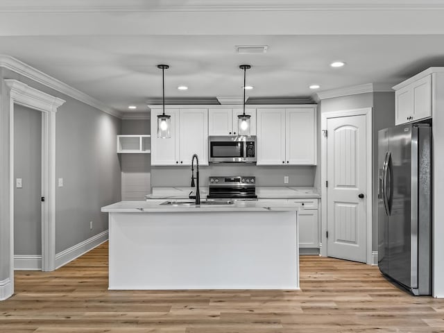 kitchen with stainless steel appliances, decorative light fixtures, a kitchen island with sink, and white cabinets