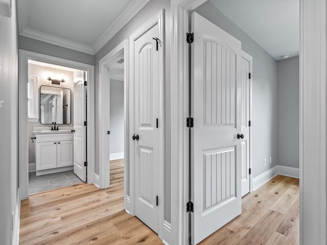 corridor with sink, crown molding, and light hardwood / wood-style floors