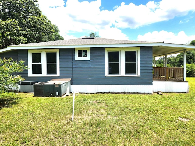 back of property featuring a jacuzzi, central AC unit, and a lawn