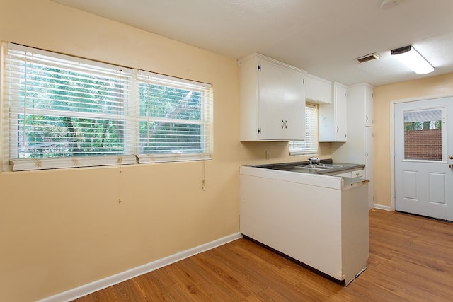 1318 W Tharpe St, Tallahassee, FL 32303 - kitchen with light wood-style floors, baseboards, and white cabinetry