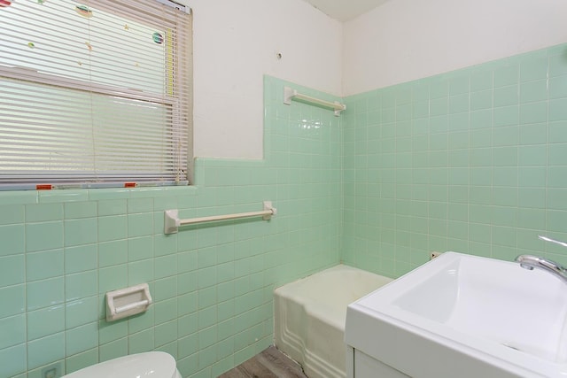 1318 W Tharpe St, Tallahassee, FL 32303 - bathroom featuring tile walls, a sink, toilet, bathing tub / shower combination, and wood finished floors