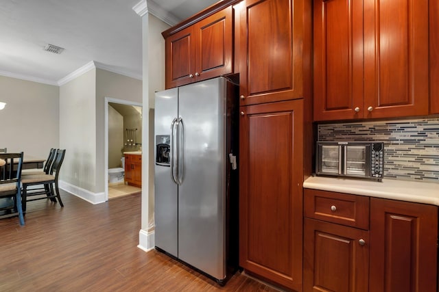 kitchen featuring tasteful backsplash, crown molding, dark hardwood / wood-style flooring, and stainless steel refrigerator with ice dispenser