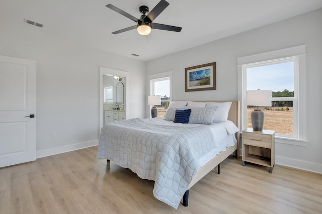 bedroom with multiple windows, light hardwood / wood-style flooring, and ensuite bathroom