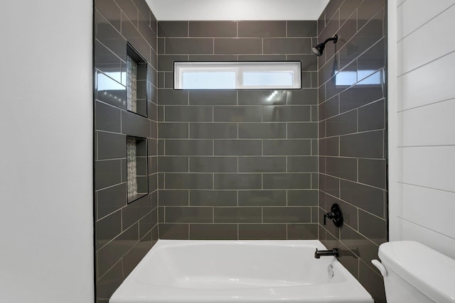 bathroom featuring tiled shower / bath combo and toilet