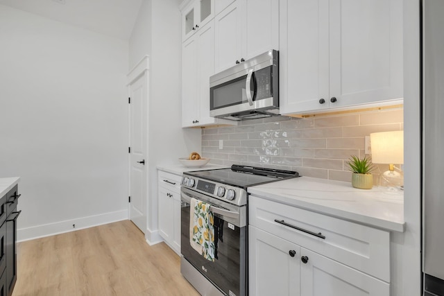 kitchen featuring light stone counters, tasteful backsplash, stainless steel appliances, light hardwood / wood-style floors, and white cabinets