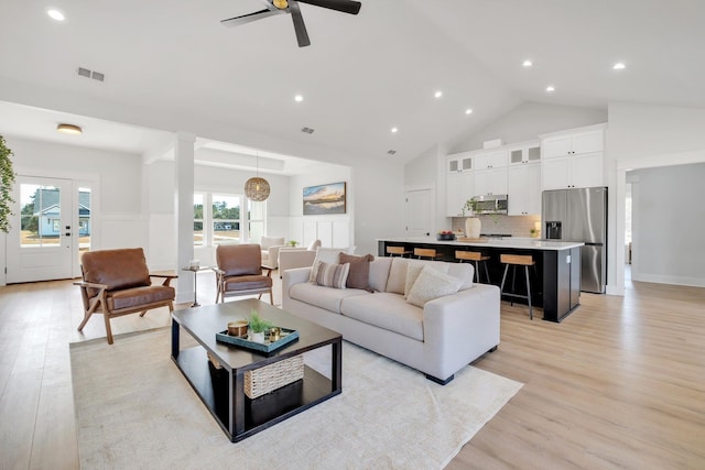 living room with ceiling fan, high vaulted ceiling, and light wood-type flooring