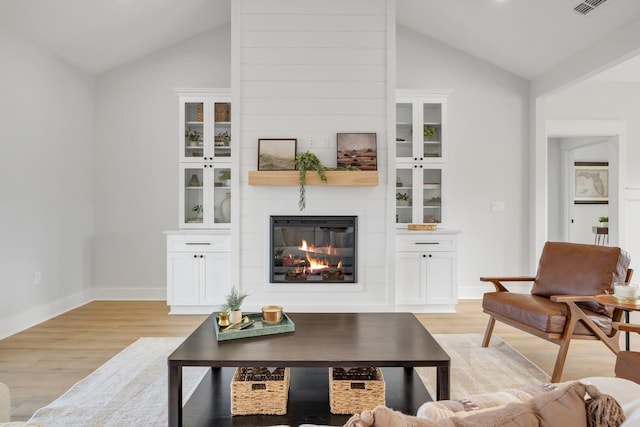 living room with a large fireplace, high vaulted ceiling, and light hardwood / wood-style flooring