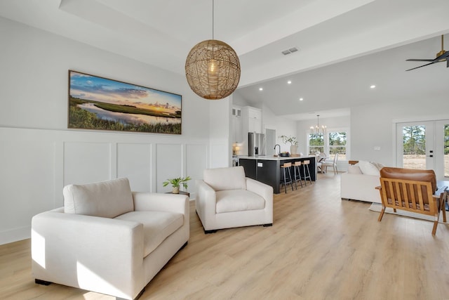 living room featuring french doors, sink, vaulted ceiling, and light hardwood / wood-style flooring