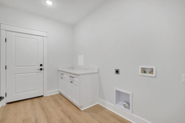 clothes washing area featuring electric dryer hookup, washer hookup, light hardwood / wood-style floors, and cabinets