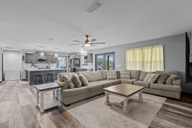 living room featuring sink, ceiling fan, and light hardwood / wood-style flooring