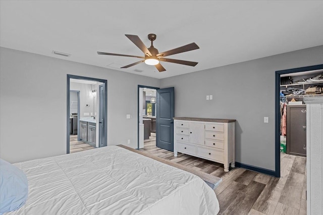 bedroom featuring ensuite bath, dark wood-type flooring, and ceiling fan