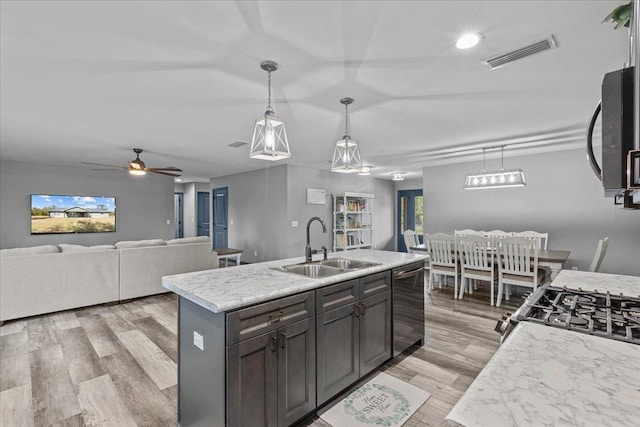 kitchen with sink, appliances with stainless steel finishes, decorative light fixtures, an island with sink, and light wood-type flooring