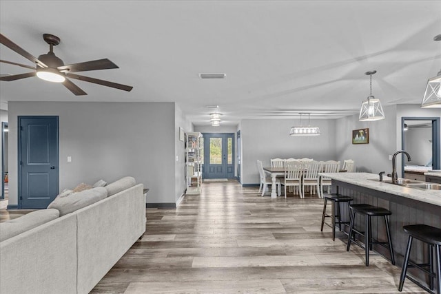 living room with hardwood / wood-style floors, ceiling fan, and sink