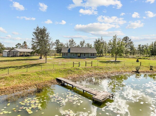 view of dock with a yard and a water view