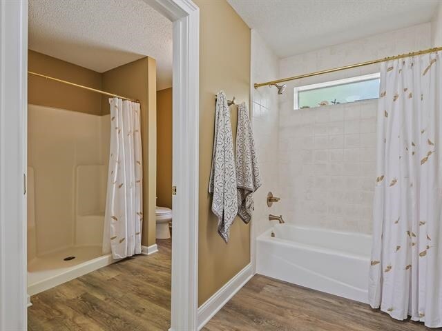 bathroom with wood-type flooring, a textured ceiling, and a shower with shower curtain