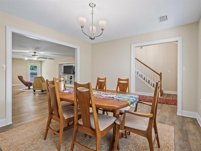 dining room featuring wood-type flooring and ceiling fan with notable chandelier