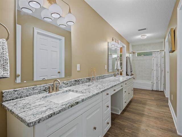 bathroom featuring hardwood / wood-style floors, shower / tub combo with curtain, and vanity