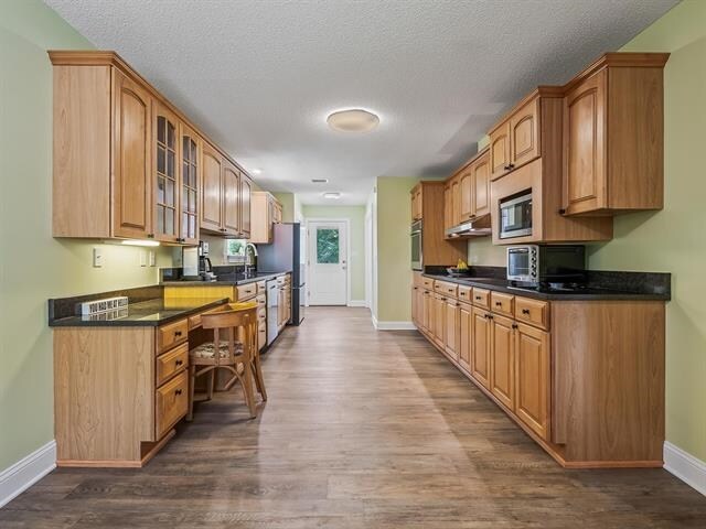 kitchen with dark wood-type flooring, a textured ceiling, sink, and stainless steel appliances