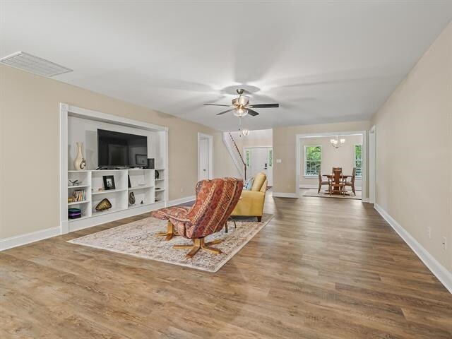 living room with hardwood / wood-style floors and ceiling fan with notable chandelier