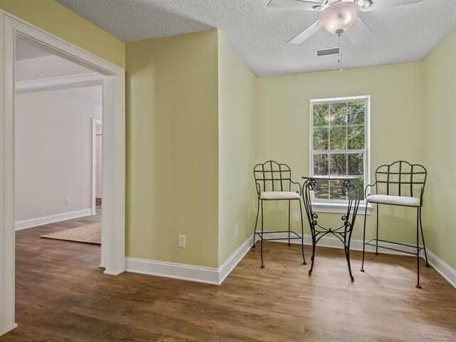 sitting room featuring hardwood / wood-style floors, ceiling fan, and a textured ceiling