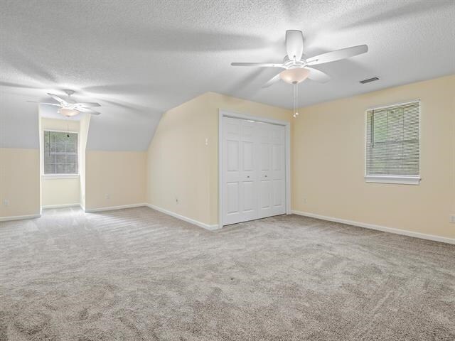 bonus room featuring vaulted ceiling, carpet flooring, and a textured ceiling