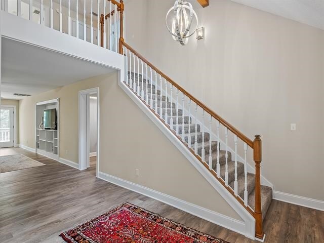 stairway featuring hardwood / wood-style flooring and a notable chandelier