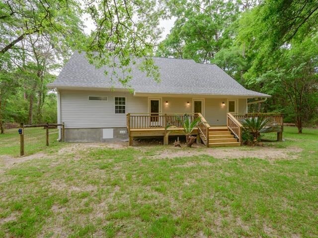 rear view of property with a deck and a lawn