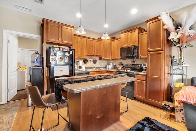 kitchen featuring black appliances, a breakfast bar, light wood-type flooring, and a center island