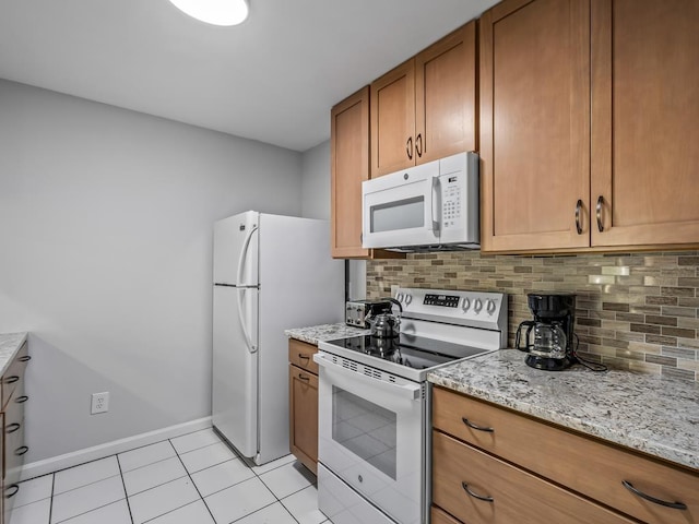 kitchen featuring light tile patterned flooring, white appliances, light stone countertops, and backsplash