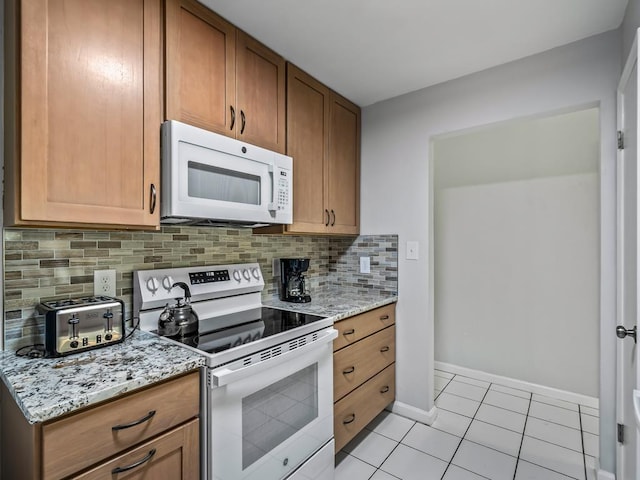 kitchen with light stone counters, white appliances, decorative backsplash, and light tile patterned floors