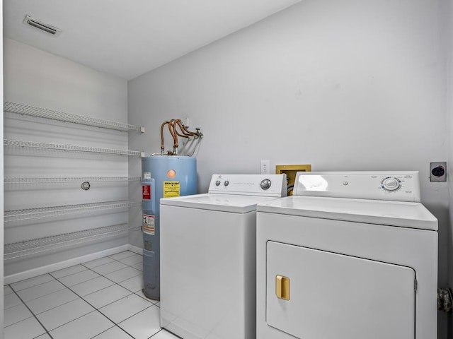 washroom with water heater, light tile patterned flooring, and washer and dryer