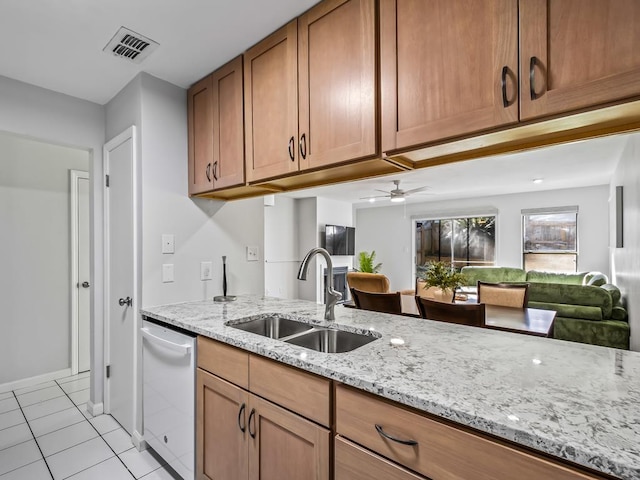 kitchen with sink, light tile patterned floors, dishwasher, ceiling fan, and light stone counters