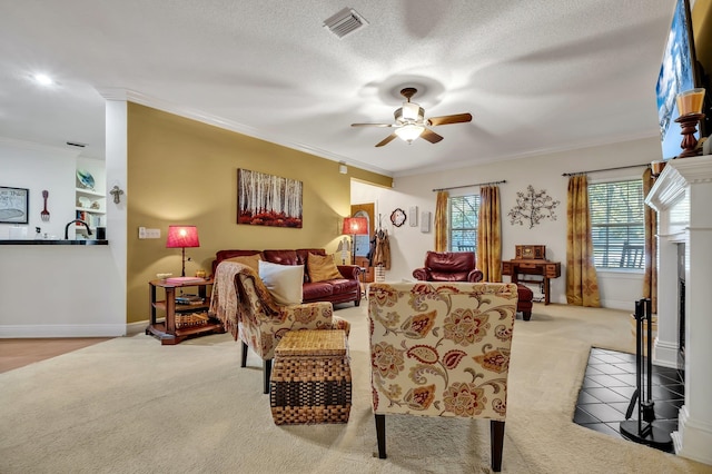 living room with ceiling fan, light colored carpet, ornamental molding, and a textured ceiling