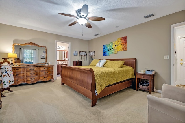 carpeted bedroom with a textured ceiling, ensuite bath, and ceiling fan