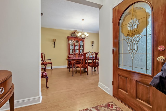 entryway with a notable chandelier, light hardwood / wood-style flooring, plenty of natural light, and ornamental molding