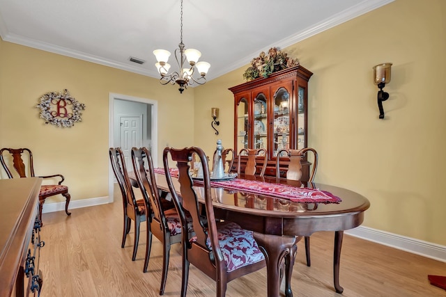 dining room featuring light hardwood / wood-style flooring, an inviting chandelier, and ornamental molding