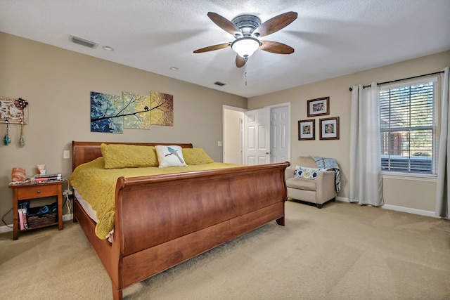 bedroom featuring light carpet, a textured ceiling, and ceiling fan