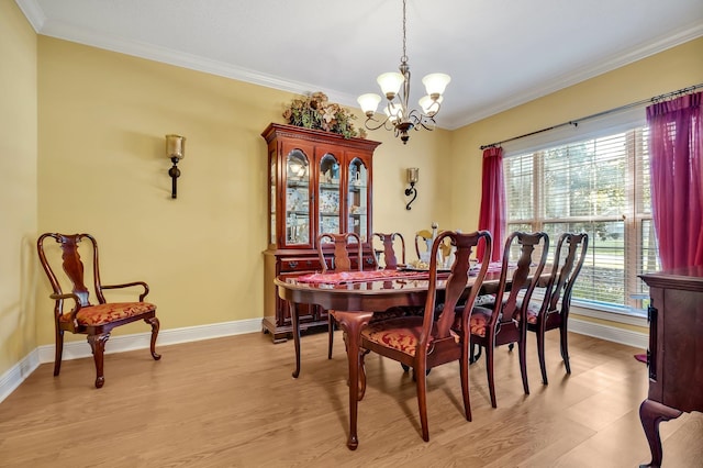 dining space featuring light hardwood / wood-style floors, an inviting chandelier, and ornamental molding