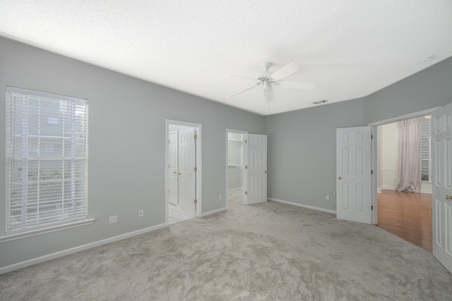 unfurnished bedroom featuring ceiling fan, light carpet, a closet, and a walk in closet